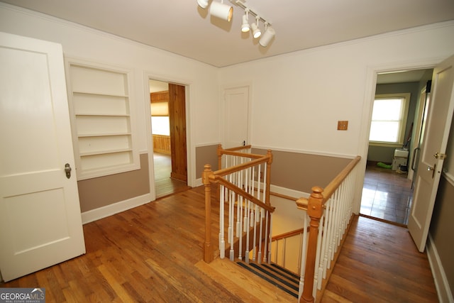 corridor featuring an upstairs landing, wood finished floors, built in shelves, and baseboards