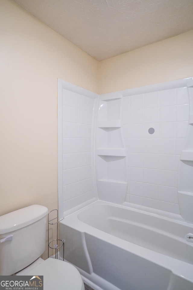 bathroom with toilet, a textured ceiling, and shower / bath combination