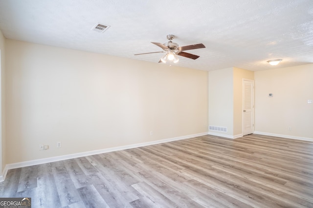 empty room with light wood-style floors, ceiling fan, baseboards, and a textured ceiling