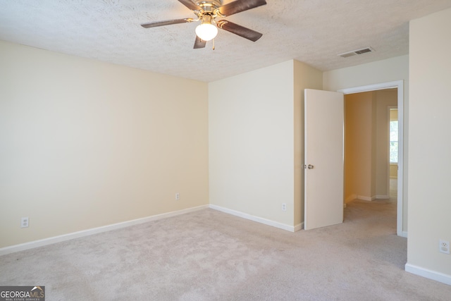empty room featuring carpet flooring, ceiling fan, a textured ceiling, and baseboards