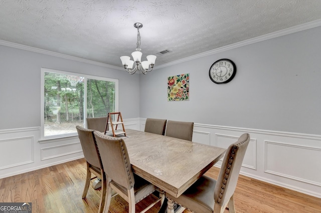 3668 Burel Mill Dr, Buford, GA 30519 - dining room featuring a chandelier, light wood finished floors, crown molding, wainscoting, and a decorative wall