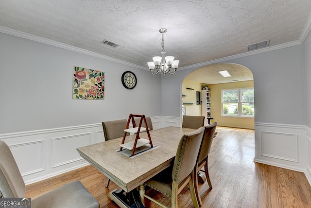 3668 Burel Mill Dr, Buford, GA 30519 - dining space with arched walkways, a chandelier, wood finished floors, wainscoting, and crown molding