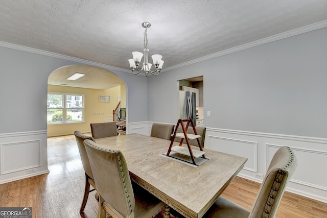 3668 Burel Mill Dr, Buford, GA 30519 - dining space with arched walkways, a chandelier, light wood finished floors, wainscoting, and crown molding