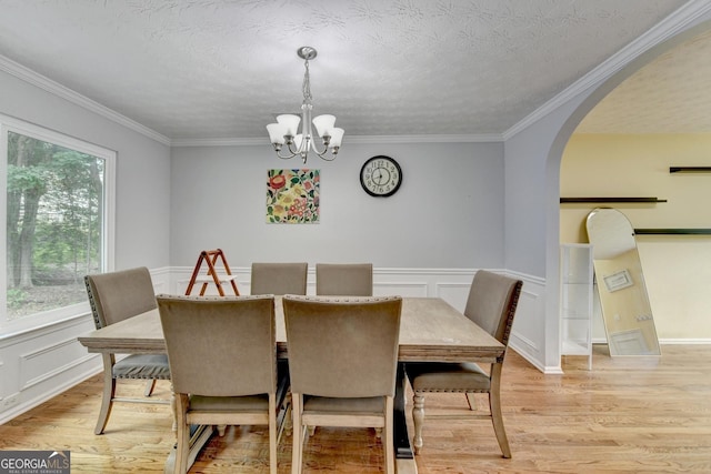 3668 Burel Mill Dr, Buford, GA 30519 - dining room featuring a chandelier, arched walkways, light wood-style flooring, ornamental molding, and a wainscoted wall