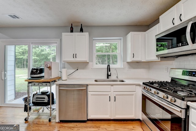 3668 Burel Mill Dr, Buford, GA 30519 - kitchen featuring stainless steel appliances, a sink, light wood-style flooring, and tasteful backsplash