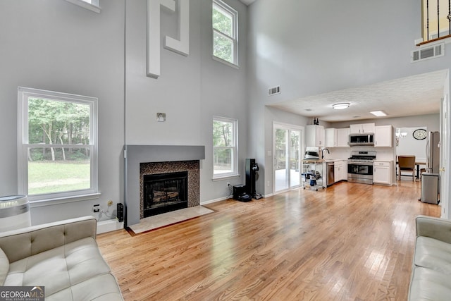 3668 Burel Mill Dr, Buford, GA 30519 - living area featuring a towering ceiling, light wood finished floors, a fireplace with flush hearth, and healthy amount of natural light