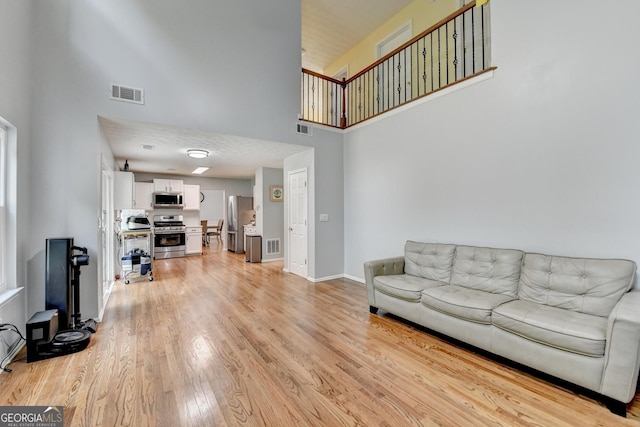 3668 Burel Mill Dr, Buford, GA 30519 - living room featuring a towering ceiling, light wood-style flooring, and baseboards