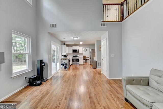 3668 Burel Mill Dr, Buford, GA 30519 - living area featuring a high ceiling, light wood finished floors, and baseboards