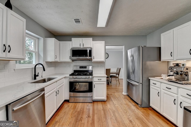 3668 Burel Mill Dr, Buford, GA 30519 - kitchen with appliances with stainless steel finishes, a sink, light wood-type flooring, and white cabinetry
