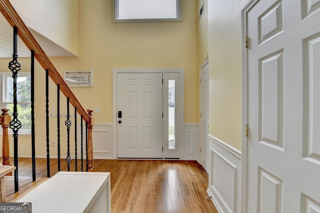 3668 Burel Mill Dr, Buford, GA 30519 - foyer entrance with wainscoting, light wood-type flooring, a decorative wall, stairway, and a towering ceiling