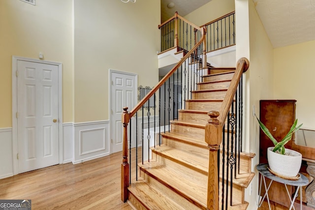 3668 Burel Mill Dr, Buford, GA 30519 - staircase with wood finished floors, a high ceiling, and wainscoting