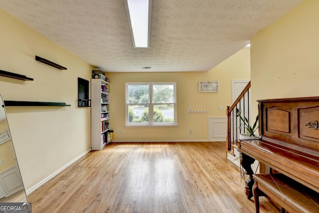 3668 Burel Mill Dr, Buford, GA 30519 - living area with light wood-style flooring, a textured ceiling, stairway, and baseboards