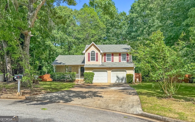 tri-level home with concrete driveway, a front lawn, roof with shingles, and an attached garage