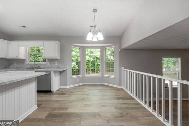 kitchen with stainless steel dishwasher, white cabinetry, a chandelier, and healthy amount of natural light