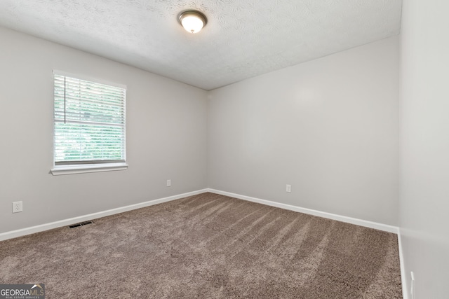spare room with carpet floors, a textured ceiling, and baseboards