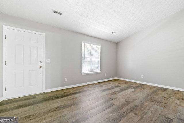 entryway featuring hardwood / wood-style flooring, baseboards, and a textured ceiling