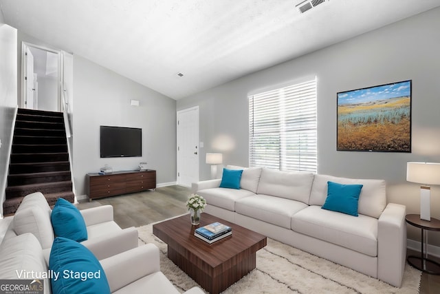 living room with lofted ceiling, wood finished floors, stairs, and baseboards