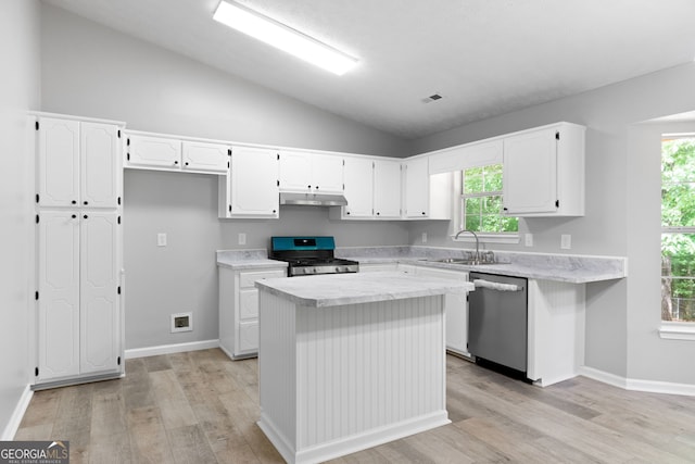 kitchen featuring stainless steel dishwasher, gas stove, under cabinet range hood, a sink, and vaulted ceiling