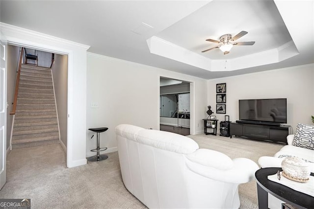 living area with light carpet, a ceiling fan, stairs, a raised ceiling, and baseboards