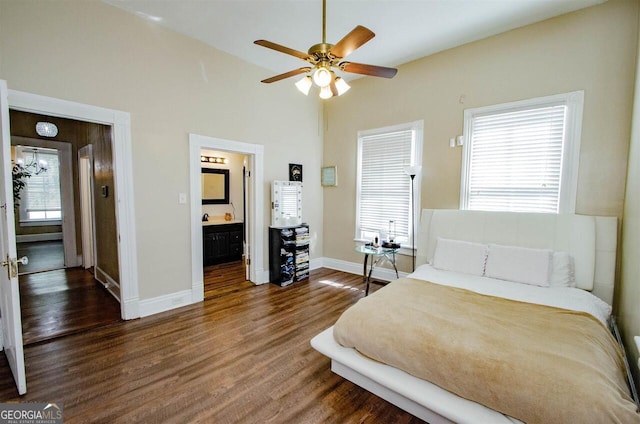 bedroom with wood finished floors, baseboards, multiple windows, ensuite bathroom, and vaulted ceiling