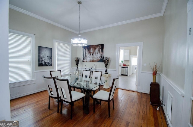 dining area with a chandelier, hardwood / wood-style flooring, ornamental molding, and a wainscoted wall