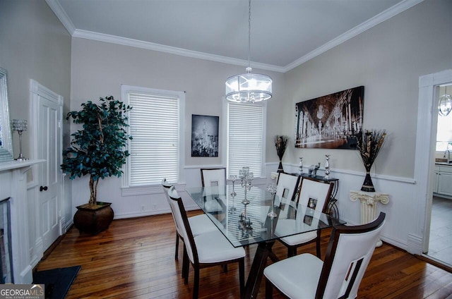 dining area featuring hardwood / wood-style flooring, a chandelier, ornamental molding, a decorative wall, and wainscoting