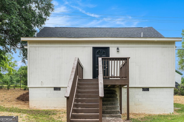 doorway to property with roof with shingles, crawl space, and fence
