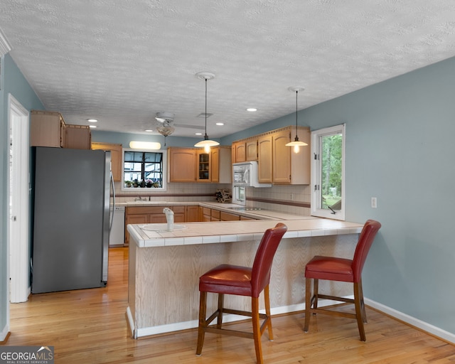 312 Flat Shoals Church Rd, Stockbridge, GA 30281 - kitchen featuring white appliances, a peninsula, light wood-style flooring, tile counters, and a textured ceiling
