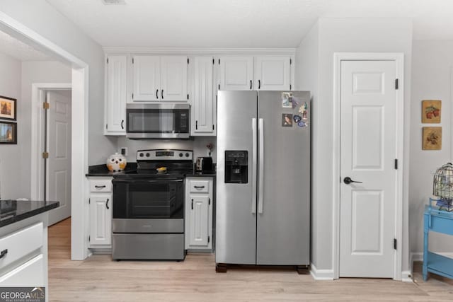 1152 Strath Clyde Way, Mcdonough, GA 30253 - kitchen with stainless steel appliances, light wood-style flooring, white cabinetry, baseboards, and dark stone countertops