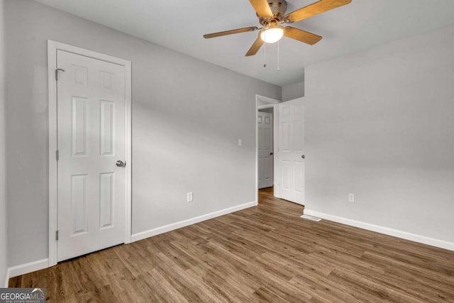 unfurnished bedroom with wood finished floors, baseboards, and a ceiling fan