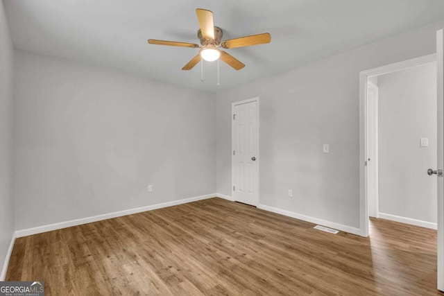 spare room featuring a ceiling fan, wood finished floors, and baseboards