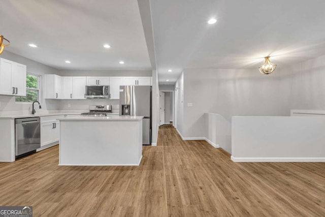 kitchen with stainless steel appliances, light countertops, light wood finished floors, white cabinetry, and baseboards