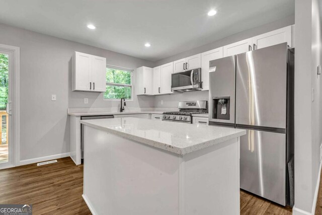 2184 Cherokee Valley Cir, Lithonia, GA 30058 - kitchen with stainless steel appliances, white cabinetry, a kitchen island, light stone countertops, and dark wood finished floors