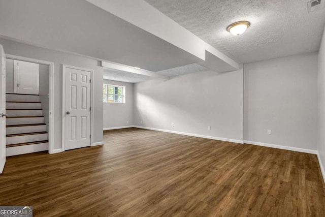 basement with wood finished floors, baseboards, a textured ceiling, and stairs