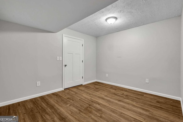 empty room with baseboards, wood finished floors, and a textured ceiling