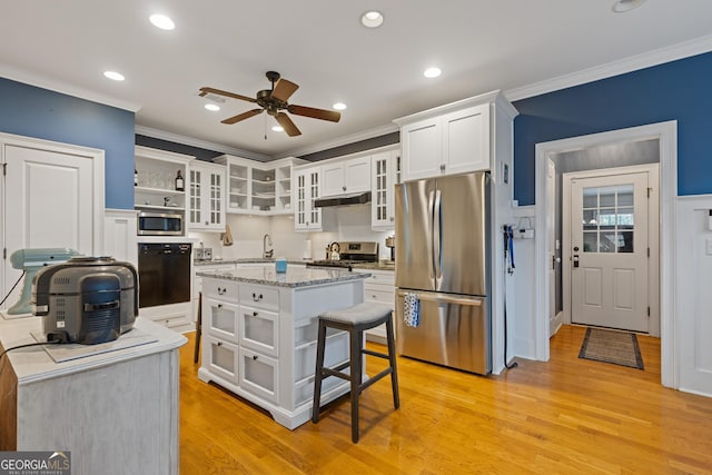 kitchen with appliances with stainless steel finishes, ornamental molding, a ceiling fan, white cabinets, and light wood-style floors