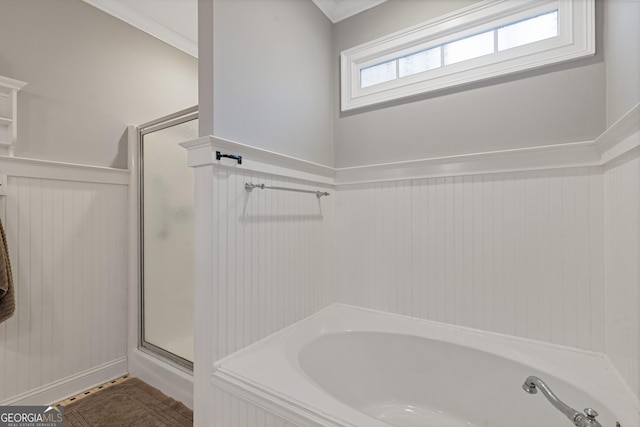 bathroom featuring a stall shower, a bath, wainscoting, and ornamental molding