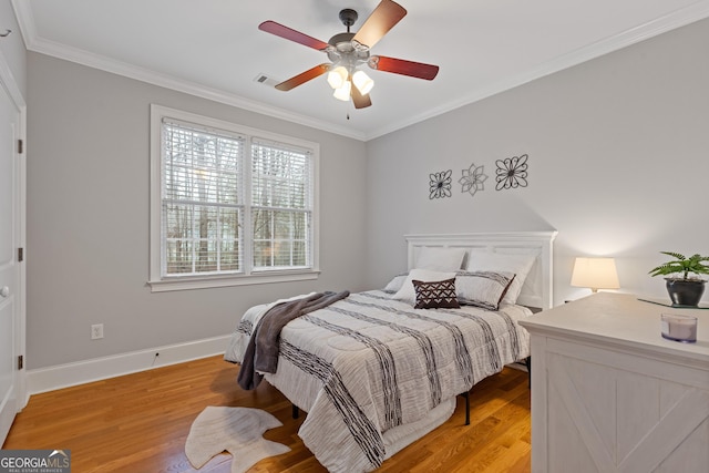bedroom featuring light wood-type flooring, ornamental molding, baseboards, and a ceiling fan