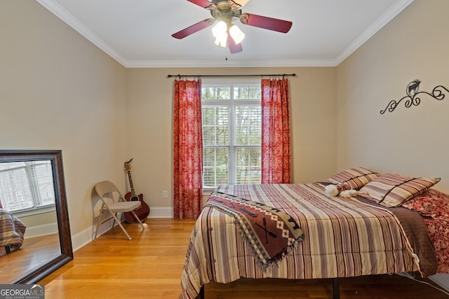 bedroom featuring crown molding, light wood finished floors, baseboards, and a ceiling fan