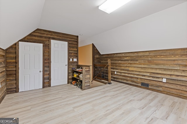 bonus room featuring lofted ceiling, wood finished floors, and wooden walls