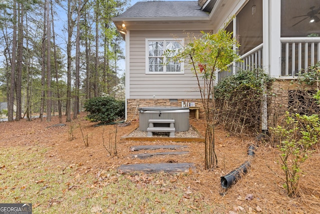 view of side of property with roof with shingles and a hot tub