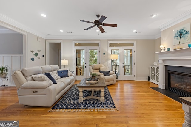 living room with french doors, ceiling fan, ornamental molding, recessed lighting, and a fireplace with flush hearth