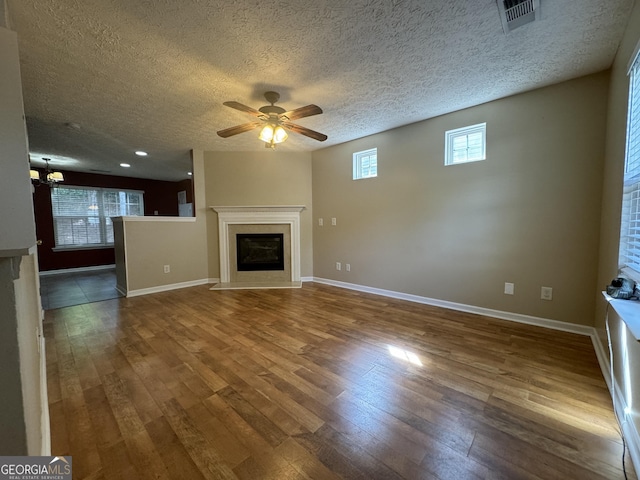 218 Osmanthus Way, Canton, GA 30114 - unfurnished living room featuring a fireplace with flush hearth, ceiling fan, wood finished floors, a textured ceiling, and a chandelier