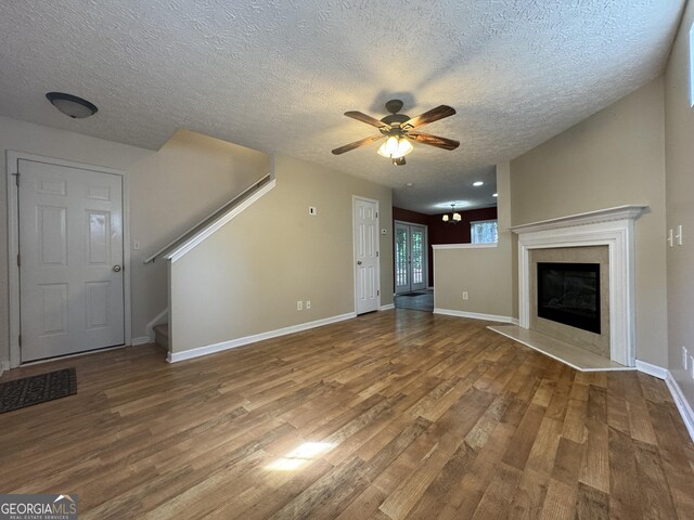 218 Osmanthus Way, Canton, GA 30114 - unfurnished living room with wood finished floors, ceiling fan, a textured ceiling, stairway, and a fireplace