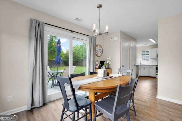 dining space featuring a chandelier, baseboards, light wood-style floors, and healthy amount of natural light