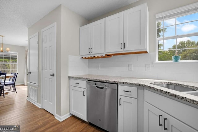 kitchen with stainless steel dishwasher, dark wood-type flooring, decorative backsplash, white cabinetry, and a textured ceiling