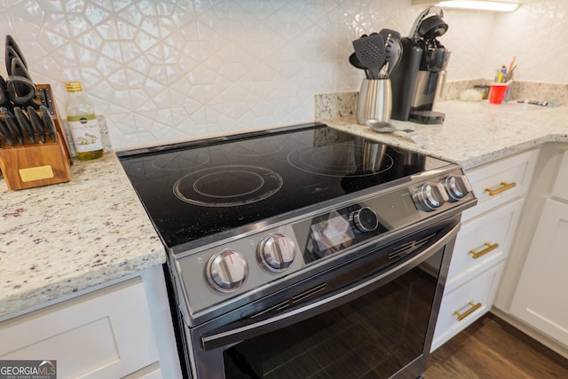 4043 Gramercy Dr, Valdosta, GA 31605 - kitchen view of stainless steel electric range, tasteful backsplash, white cabinetry, and light stone counters