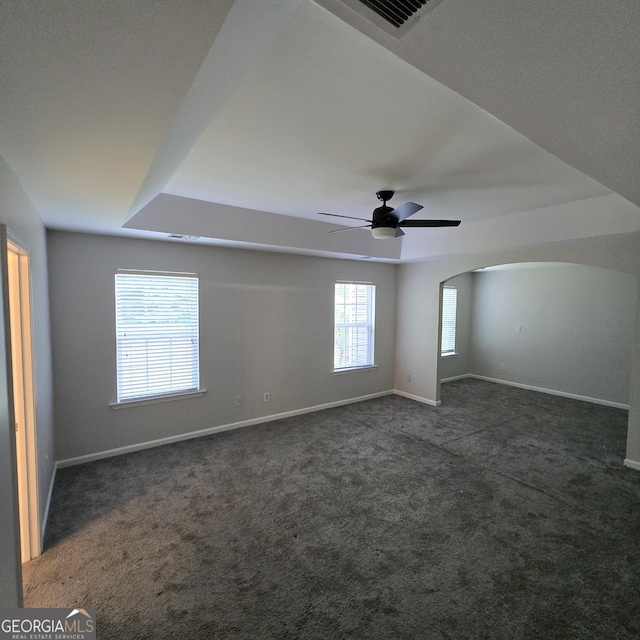 590 Dot Dr, Atlanta, GA 30349 - empty room featuring dark colored carpet, baseboards, a ceiling fan, and arched walkways