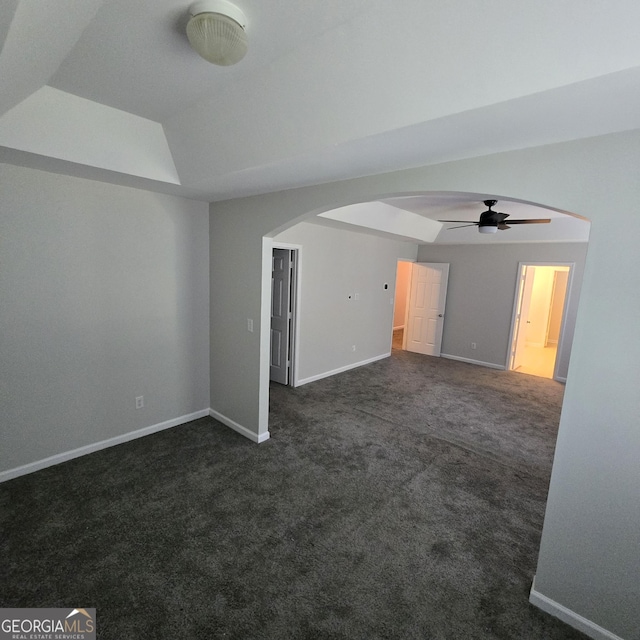 590 Dot Dr, Atlanta, GA 30349 - empty room featuring ceiling fan, arched walkways, dark carpet, baseboards, and lofted ceiling