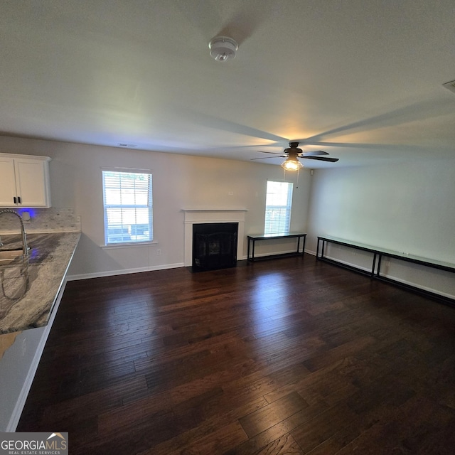 590 Dot Dr, Atlanta, GA 30349 - unfurnished living room featuring dark wood-type flooring, a ceiling fan, a fireplace with flush hearth, and plenty of natural light